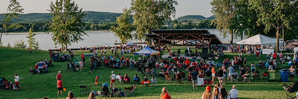 A view of the stage and the Ottawa River behind with a crowd looking at a show.