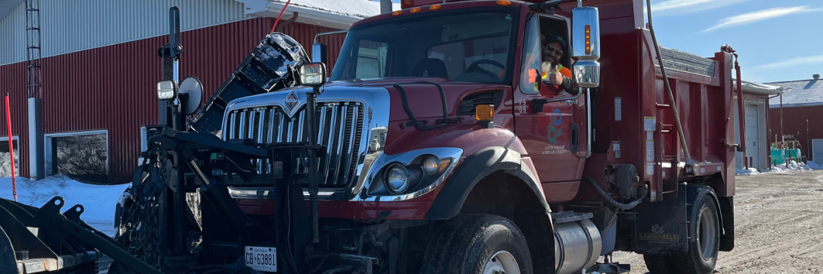 A red snowplow truck in front of the municipal garage.