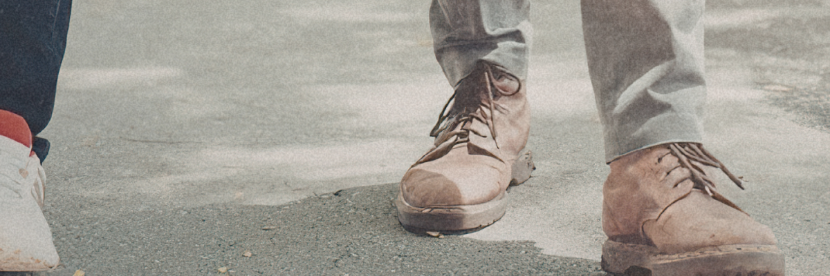 A close up on 2 persons feets walking towards the camera on a sidewalk