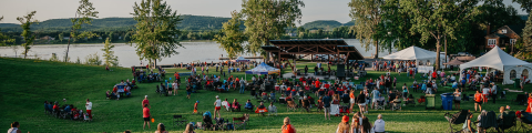 A view of the stage and the Ottawa River behind with a crowd looking at a show.
