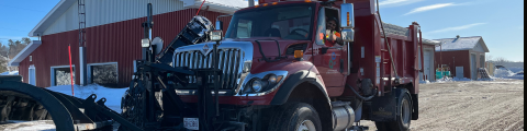 A red snowplow truck in front of the municipal garage.