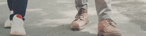 A close up on 2 persons feets walking towards the camera on a sidewalk